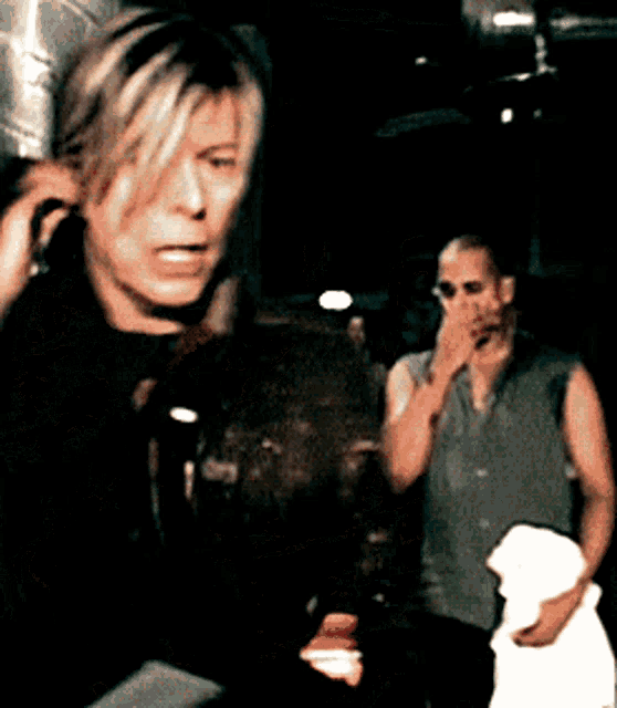 a man is covering his mouth with his hand while another man looks on