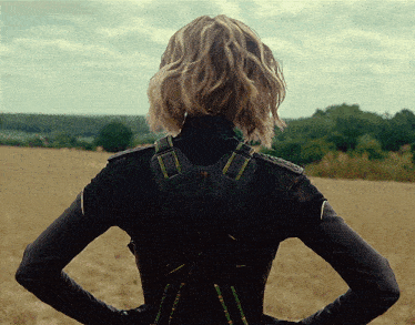 a woman standing in a field with her back to the camera