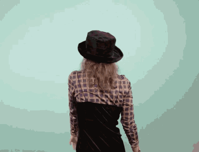 a woman wearing a top hat and plaid shirt