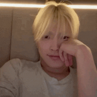 a man with blonde hair is sitting on a couch with his hand on his chin .