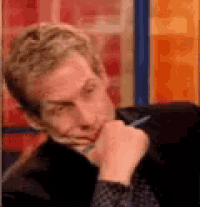 a man is sitting down with his hand on his chin and a pen in his hand .