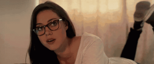 a woman wearing glasses and a white shirt is laying on her stomach .