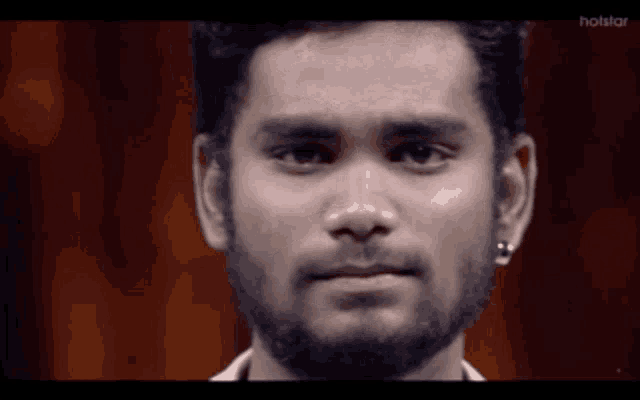 a close up of a man 's face with a hotstar logo in the background