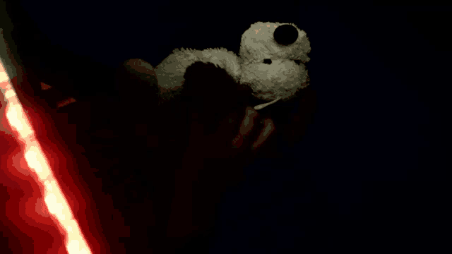 a person is holding a stuffed animal in their hand in the dark