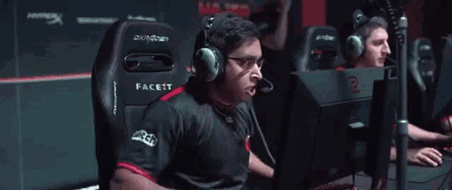 a man is sitting in a gaming chair with his arms in the air while wearing headphones .