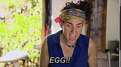 a woman wearing a headband and a blue shirt is screaming and saying egg !