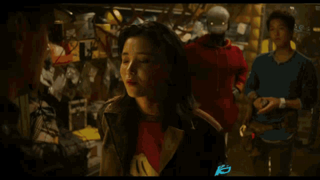 a woman in a red shirt is looking up at a man in a blue shirt in a dark room
