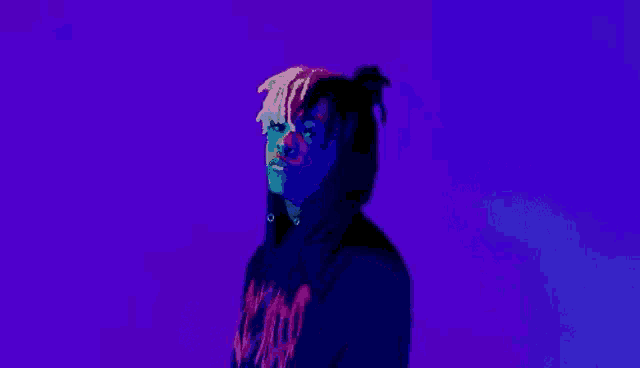 a man in a hoodie is standing in front of a purple background holding a gun .