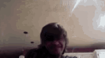 a close up of a person 's face in a dark room with a ceiling in the background .