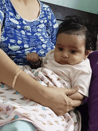 a woman is holding a baby in her arms and the baby is wearing a shirt with ice cream cones on it