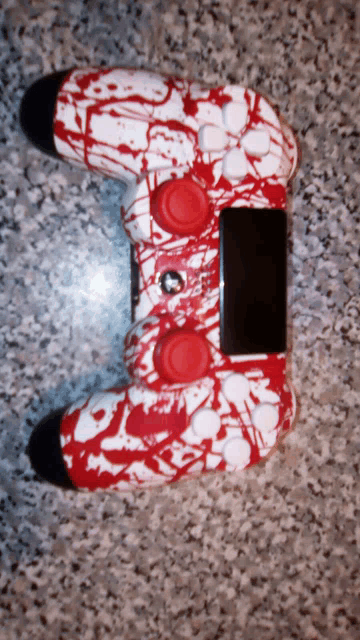 a video game controller with red and white paint splatter