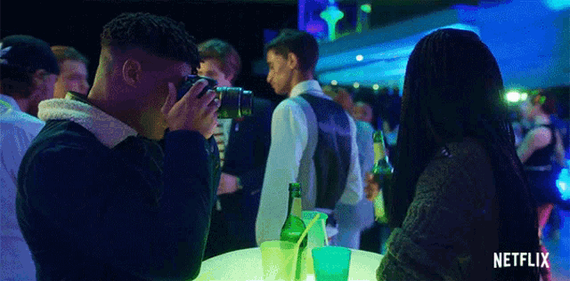 a man is taking a picture of a woman at a party with a netflix logo in the background