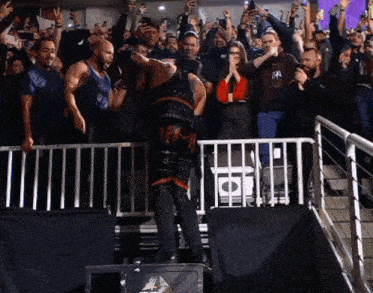 a crowd of people watching a wrestling match with a man wearing a t-shirt that says ' a '