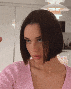 a woman wearing a pink sweater and a gold necklace