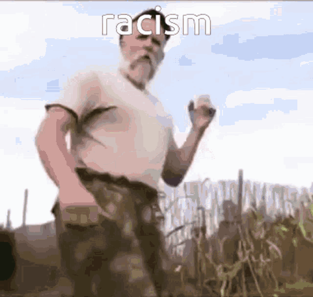 a man with a beard is standing in a field with the word racism written on the bottom