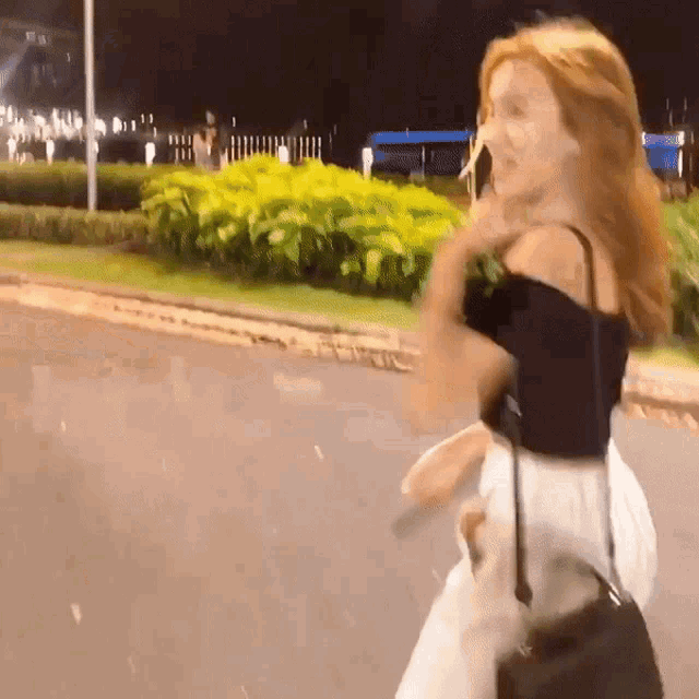 a woman with red hair is walking down a street
