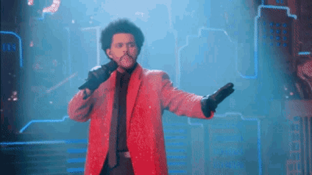 a man in a red jacket is singing into a microphone