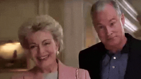 a man and a woman are standing next to each other and smiling . the woman is wearing a pink jacket .