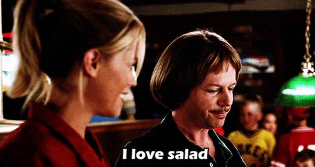 a man and a woman are standing next to each other and the man is saying i love salad