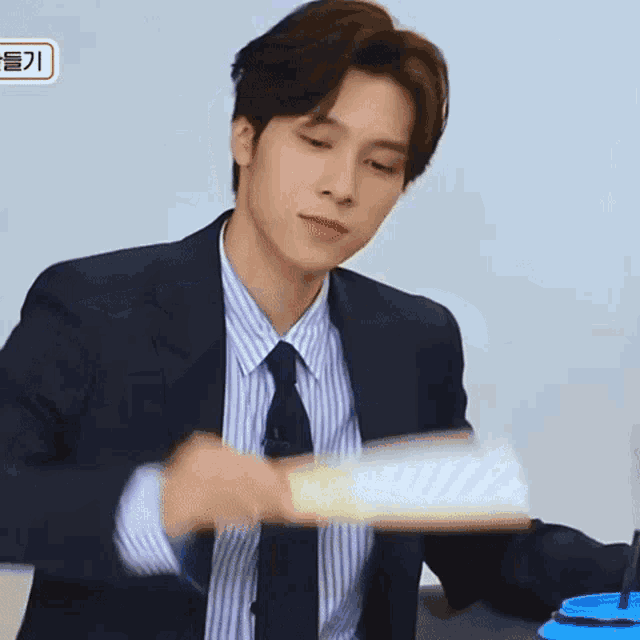 a man in a suit and tie is holding a piece of paper in his hands .