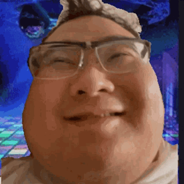 a man wearing glasses is smiling in front of a disco floor