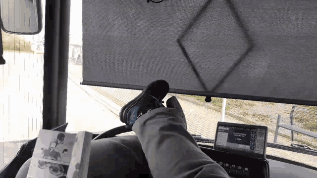 a person laying on a bus with their feet up and a laptop on the dashboard