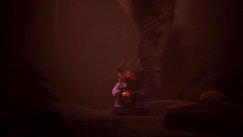 a purple lego figure is sitting in a dark cave holding an orange ball