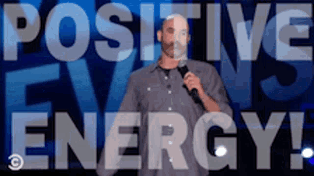 a man is holding a microphone in front of a blue background that says positive energy