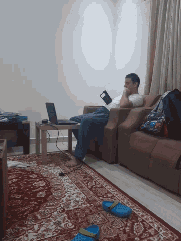 a man sits on a couch looking at his cell phone