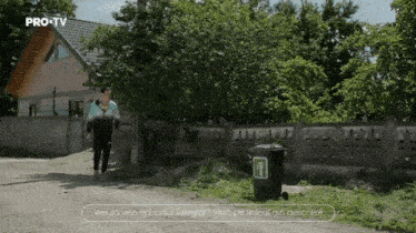 a man standing next to a trash can that says pro tv on the top
