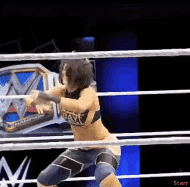 a woman is standing in a wrestling ring with a wwe belt in the background .
