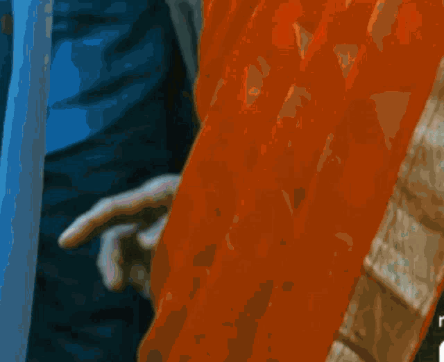 a close up of a person 's hand holding an orange curtain