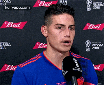a soccer player is talking into a microphone in front of a budweiser banner .