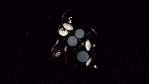 a man playing drums in a dark room with a smokey background