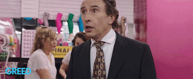 a man in a suit and tie is standing in front of a sign that says sale