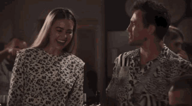 a woman in a leopard print top smiles next to a man