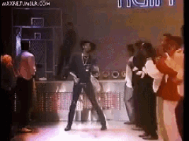a man in a hat is dancing on a stage in front of a crowd of people .