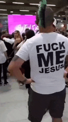 a man with a mohawk is wearing a shirt that says " fuck me jesus "