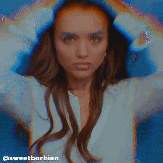 a woman in a white shirt is holding her hair in front of a blue background