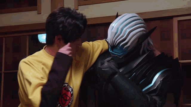 a man wearing a yellow shirt with a smiley face on it is hugging another man