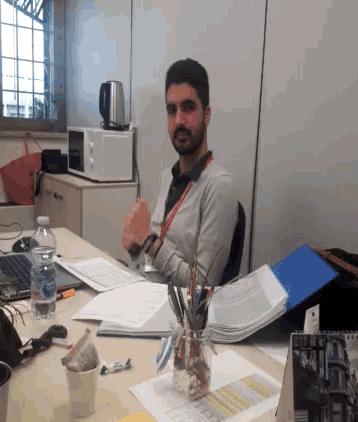 a man sitting at a desk with a bottle of aquafina water on it