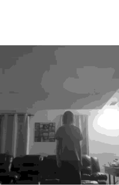 a black and white photo of a man standing in a living room .
