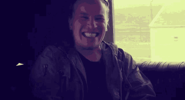 a man wearing a black shirt and a jacket is smiling