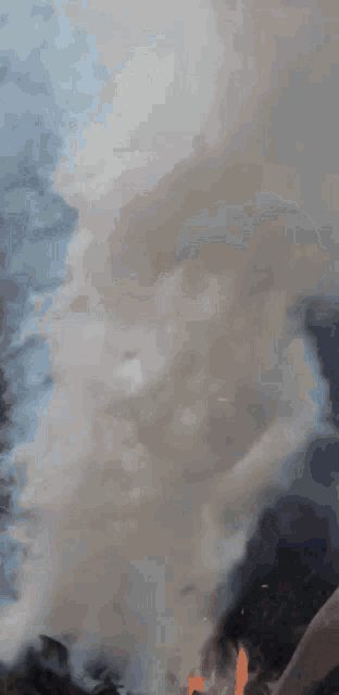 a man in a blue hat is standing in front of a large pile of smoke
