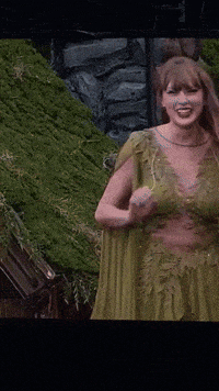 a woman in a green dress is laughing in front of a hill of grass