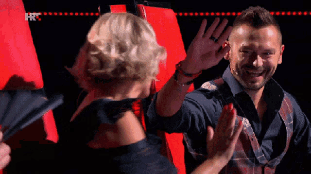 a man and woman are giving each other a high five in front of a red wall that has the letters hr on it