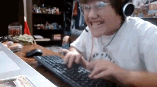a young boy wearing headphones and glasses is typing on a keyboard