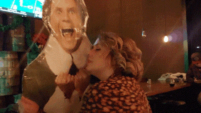 a woman is kissing a cardboard cut out of a man