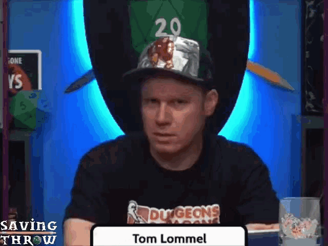 a man wearing a dungeons and dragons hat is sitting at a table