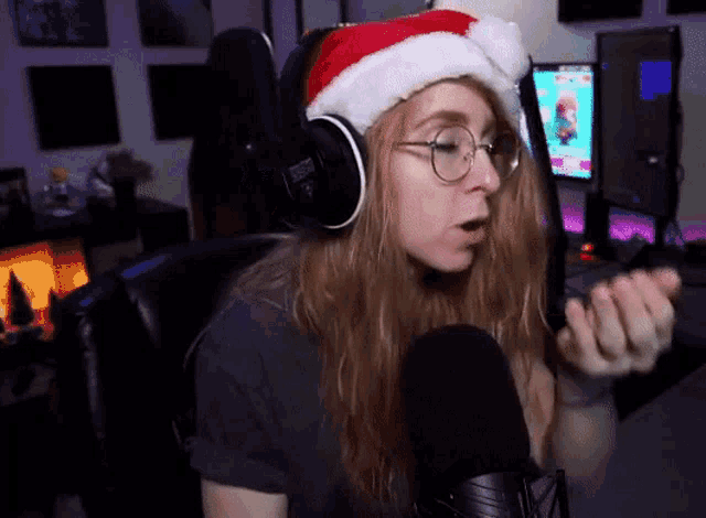 a woman wearing a santa hat is talking into a microphone